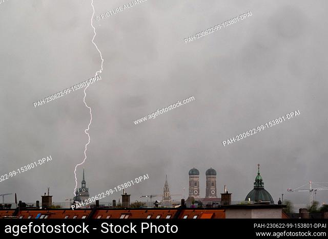 22 June 2023, Bavaria, Munich: A thunderstorm with lightning strikes the roofs of the Bavarian capital in the evening hours