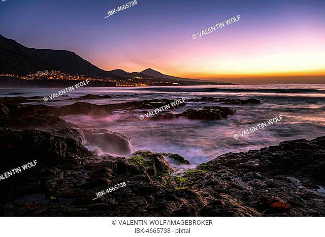 Rocky coast and sea at sunset, backlit place Bajamar and volcano Pico del Teide, Punta del Hidalgo, Tenerife, Canary Islands, Spain