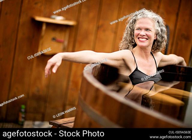 Smiling mature woman in hot tub at eco retreat