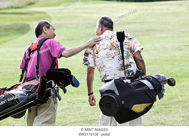 Two senior friends golfing and walking on a fairway toward their next shots