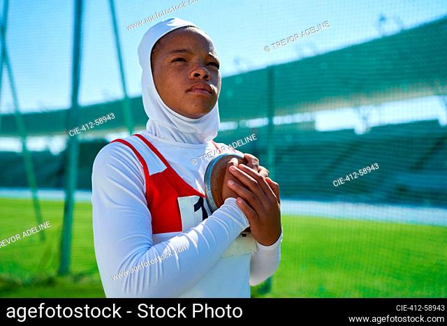 Determined female track and field athlete preparing to throw discus