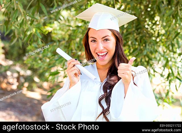 Attractive Mixed Race Girl Celebrating Graduation Outside In Cap and Gown with Diploma in Hand