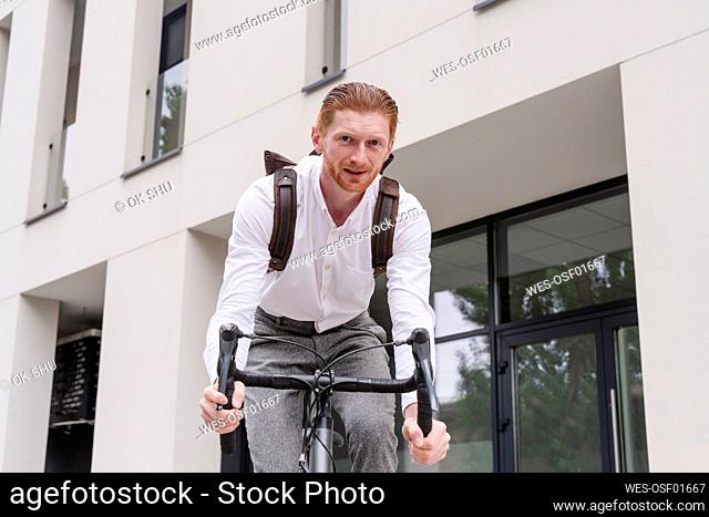 Businessman riding bicycle outside office