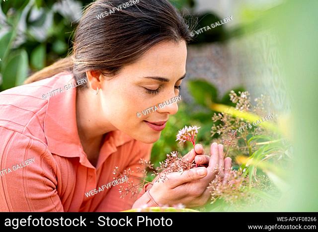 Young woman smelling fresh flowers in garden