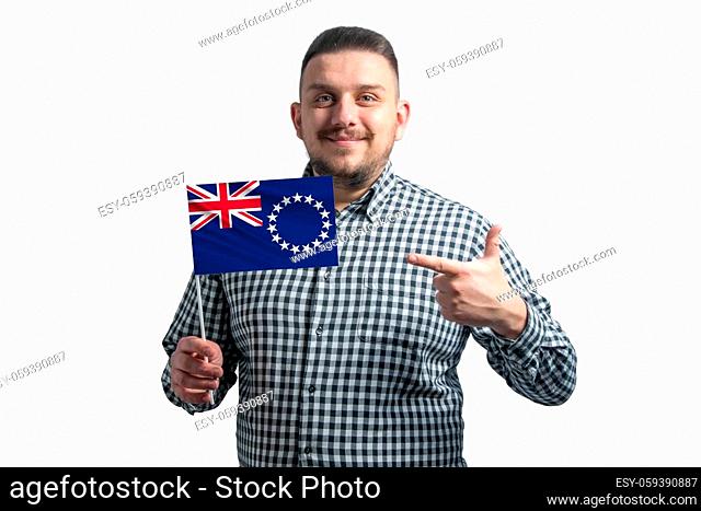 White guy holding a flag of Cook Islands and points the finger of the other hand at the flag isolated on a white background