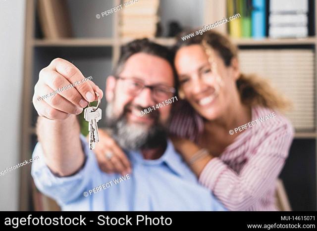Happy couple showing keys of their new house or office. Portrait of smiling wife with husband holding key to their new apartment