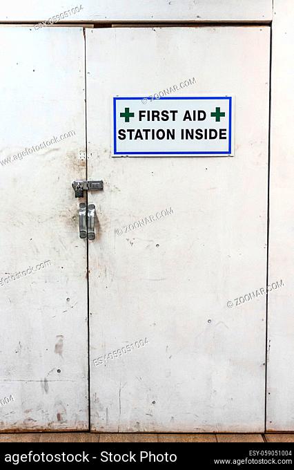 Temporary first aid station dirty white doors and sign at construction site under artificial light