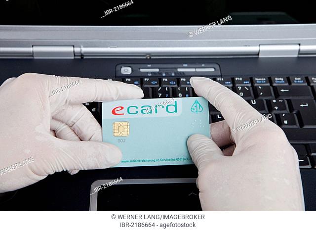 Hacker using a laptop, holding a health insurance card and wearing latex gloves to leave no traces, symbolic image for welfare fraud