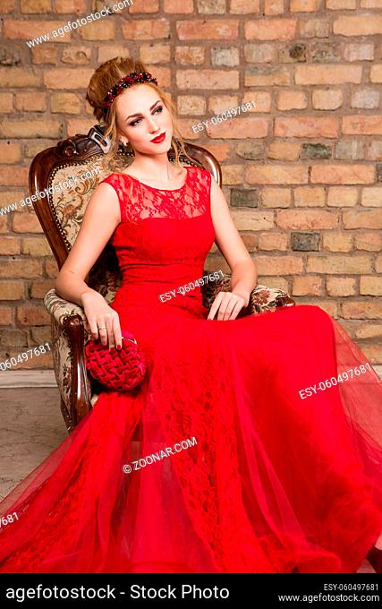 beautiful red hair young woman in red wedding gown. bride with fashion hairstyle. studio shot