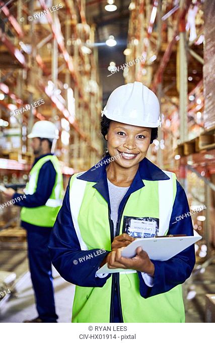 Portrait confident female manager with clipboard in distribution warehouse