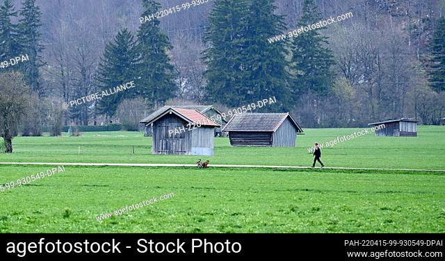 15 April 2022, Bavaria, Farchant: A walker is out in a rain gap. Very changeable weather on Good Friday in Bavaria. Photo: Angelika Warmuth/dpa