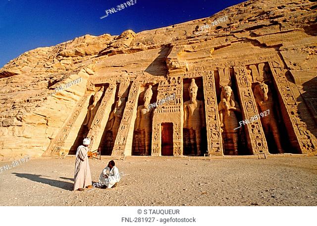 Two people in front of Egyptian temple, Nefertaris Temple Of Hathor, Abu Simbel, Egypt