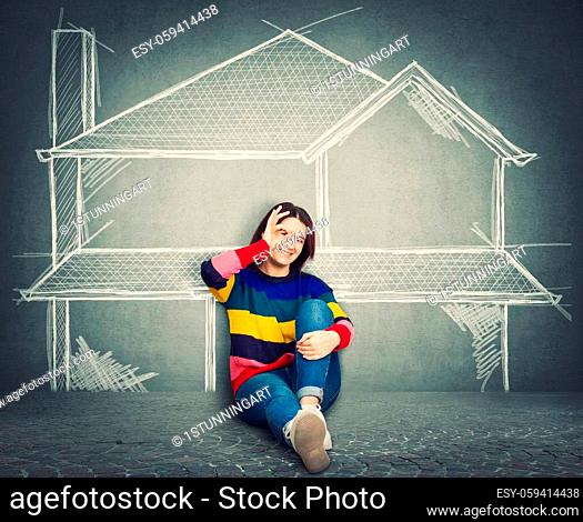 Casual young woman sitting on the floor looking through fingers gesture as spyglass searching for a new house to move. Imagining a home sketch drawn on...