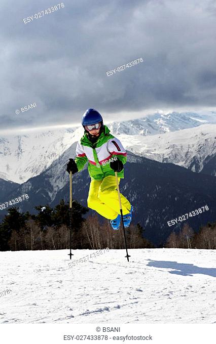 Young skier jump with ski poles in sun winter mountains and cloudy gray sky. Caucasus Mountains. Hatsvali, Svaneti region of Georgia
