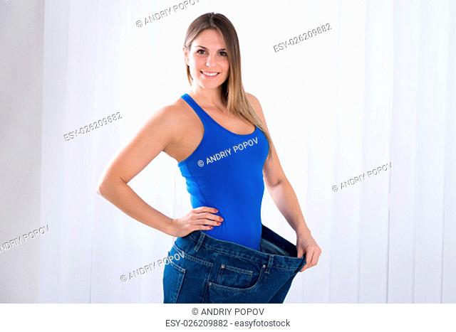 Happy Young Woman Showing Her Weightloss By Wearing Old Jeans
