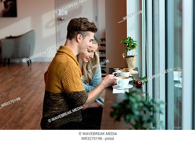 Couple using mobile phone in cafe