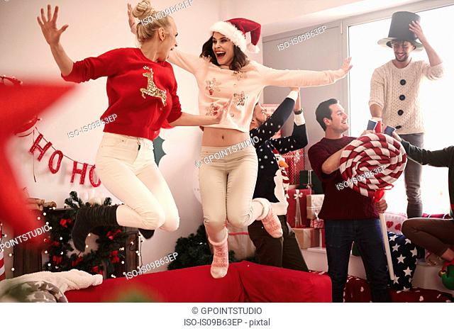 Young women jumping on sofa at christmas party
