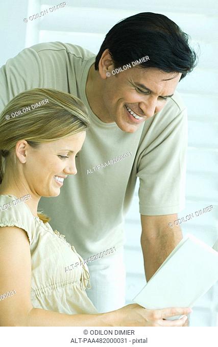 Couple reading book together, both smiling, close-up