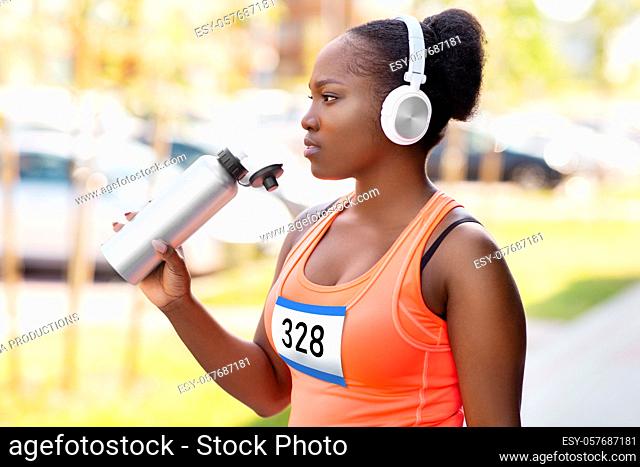 african female marathon runner drinking water
