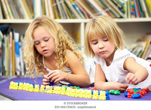 Two Elementary Pupils Counting Together In Classroom