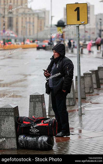 RUSSIA, MOSCOW - OCTOBER 16, 2023: A man with luggage waits for a taxi car in Komsomolskaya Square during rain. Mikhail Sinitsyn/TASS