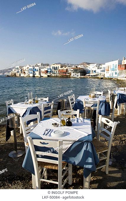 View along street with restaurants and bars, windmills in background, Little Venice, Mykonos-Town, Mykonos, Greece