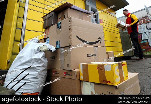 22 December 2020, Mecklenburg-Western Pomerania, Rostock: In front of a DHL Packstation, Matthias Peters has stacked up parcel shipments that he has either...