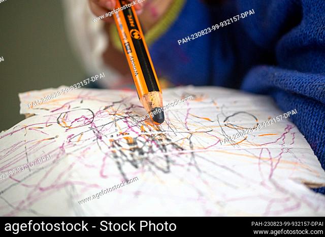 SYMBOL - 01 July 2023, Berlin: A toddler draws on his mom's lap with a colored pencil on a piece of cardboard. Photo: Fernando Gutierrez-Juarez/dpa