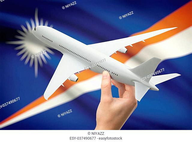 Airplane in hand with national flag on background - Marshall Islands