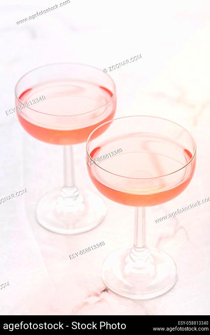 Two glasses of pink rose wine on white marble background
