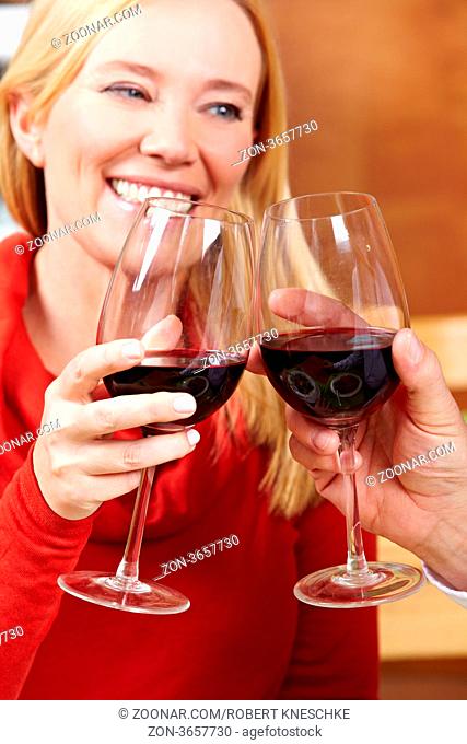 Älteres lachendes Paar prostet sich mit Rotwein im Restaurant zu