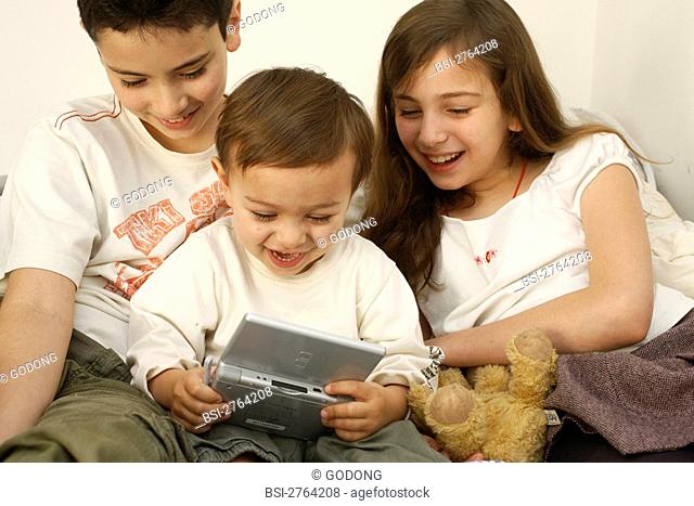 Brothers and sister playing to a video game Nintendo DS