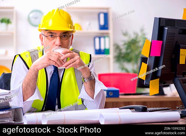 Old male architect working in office