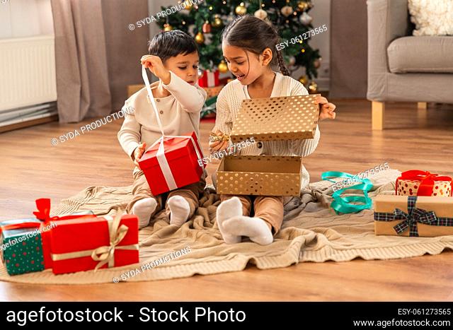 happy children opening christmas gifts at home