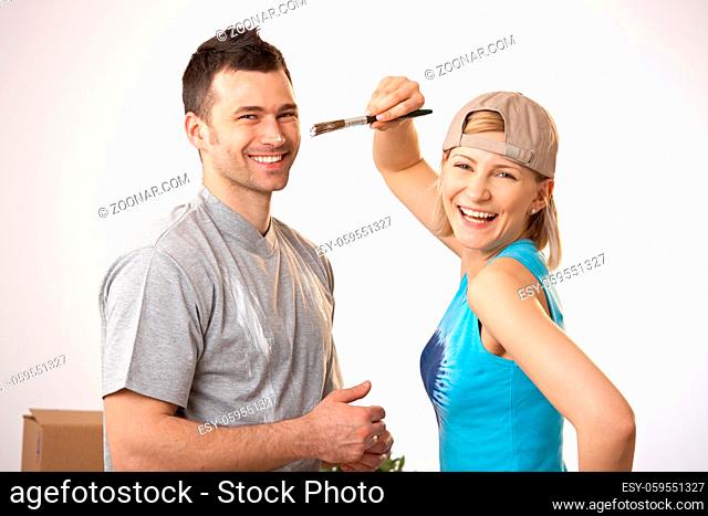 Portrait of happy couple painting together, laughing