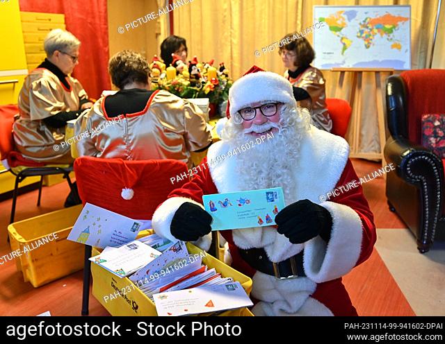 14 November 2023, Brandenburg, Himmelpfort: Santa Claus sits in the Christmas post office after arriving and shows one of many letters with wish lists