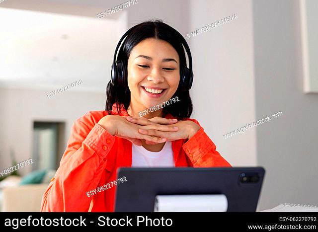 Image of biracial woman in headphones smiling during video call on tablet at home, copy space