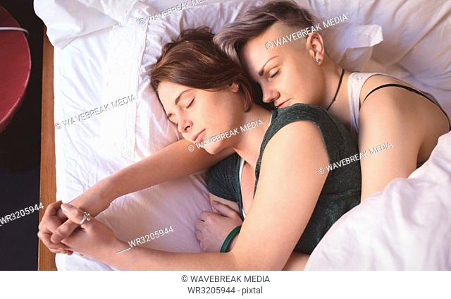 Lesbian couple sleeping on bed in bedroom