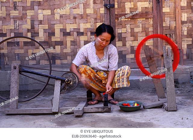 Jinghpaw woman spinning thread onto a bobbin for weaving at a weavers shop