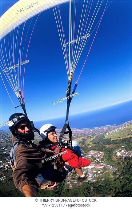 Two seater paraglider flying over Saint Leu countryside, Reunion Island (France), Indian Ocean