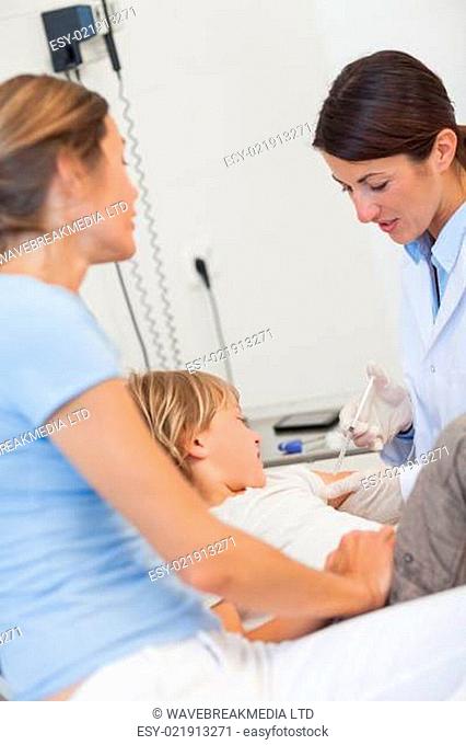 Serious doctor giving child an injection in examination room