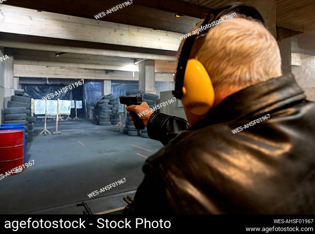 Senior man aiming with a pistol in shooting range