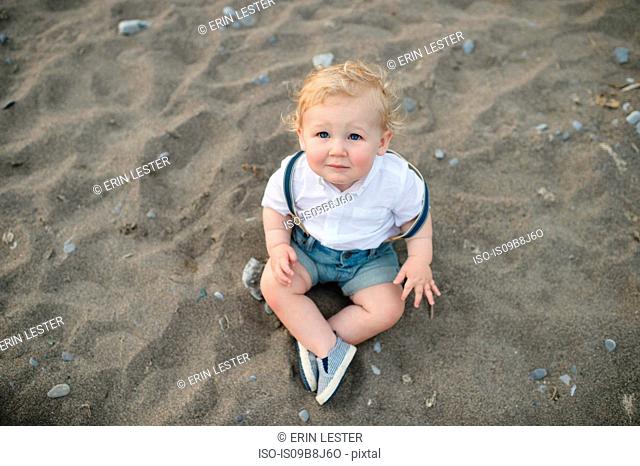 Overhead portrait of male toddler sitting on sand