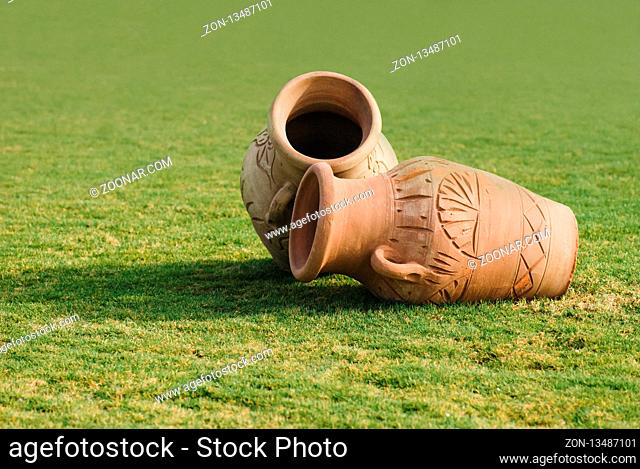 Two Clay amphora jug, old ceramic vases on green grass lawn. Sunny day