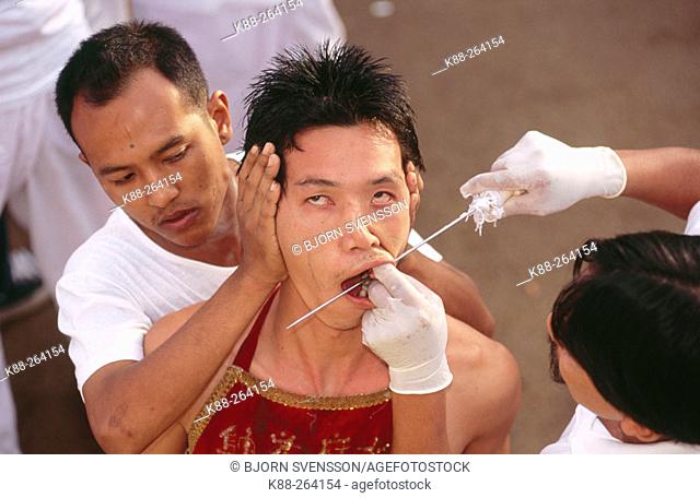 Medium in trance gets pierced by priest. Vegetarian Festival in Phuket. South Tahiland