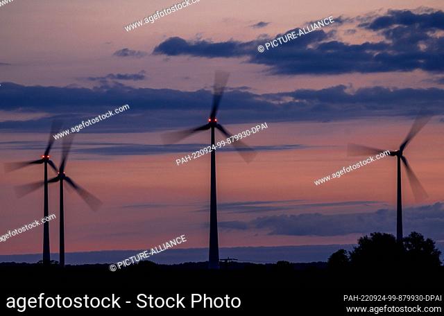 24 September 2022, Mecklenburg-Western Pomerania, Mühlen Eichsen: Wind turbines turn before sunrise and are marked by red warning lights