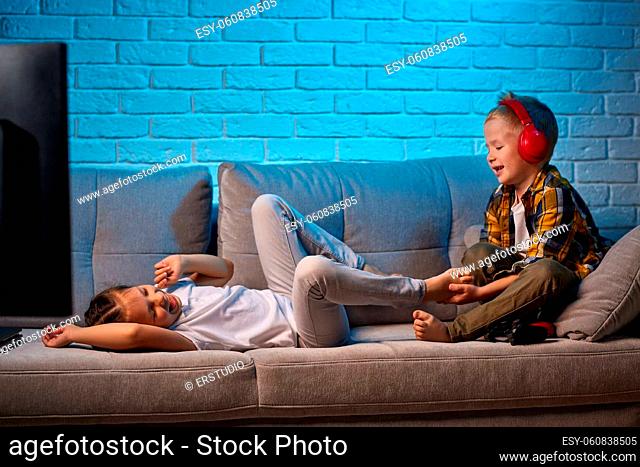 cheerful boy and girl tickle fun while sitting together on the couch
