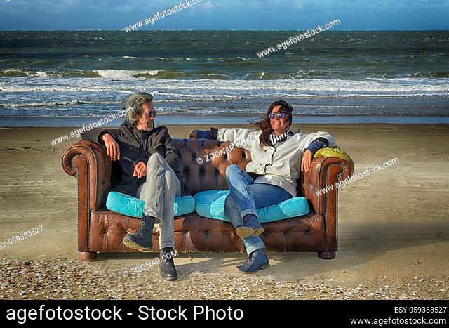 Paar auf einem verlassenen Sofa am Strand der Nordsee in Holland couple sitting on a lost sofa on the beach of the North Sea in Holland