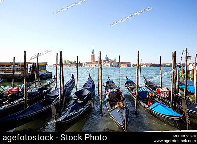 Gondolas moored near Piazza San Marco. In the background, the island of San Giorgio Maggiore. Venice (Italy), June 1st, 2021