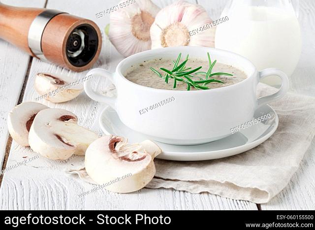 Mushroom cream soup with herbs and spices in white bowl